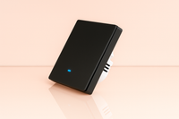 Un interrupteur connecté noir sur un fond rose